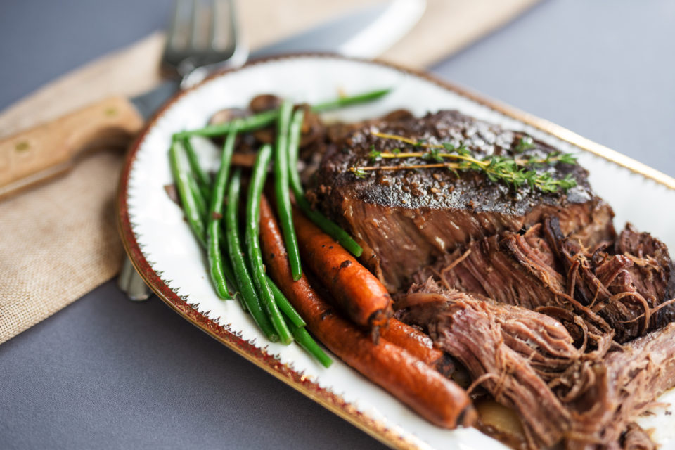 Roast beef, green beans, and carrots on a white serving platter