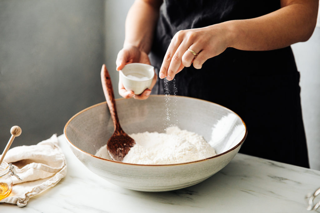 Woman sprinkling salt in flour before mixing