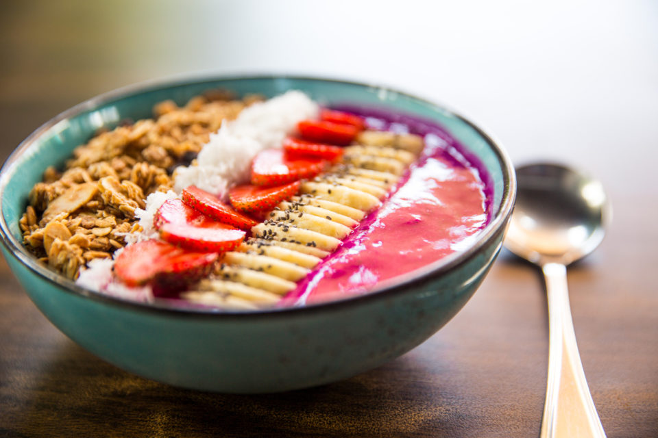 Smoothie bowl with strawberries, granola, chia seeds, and banana.