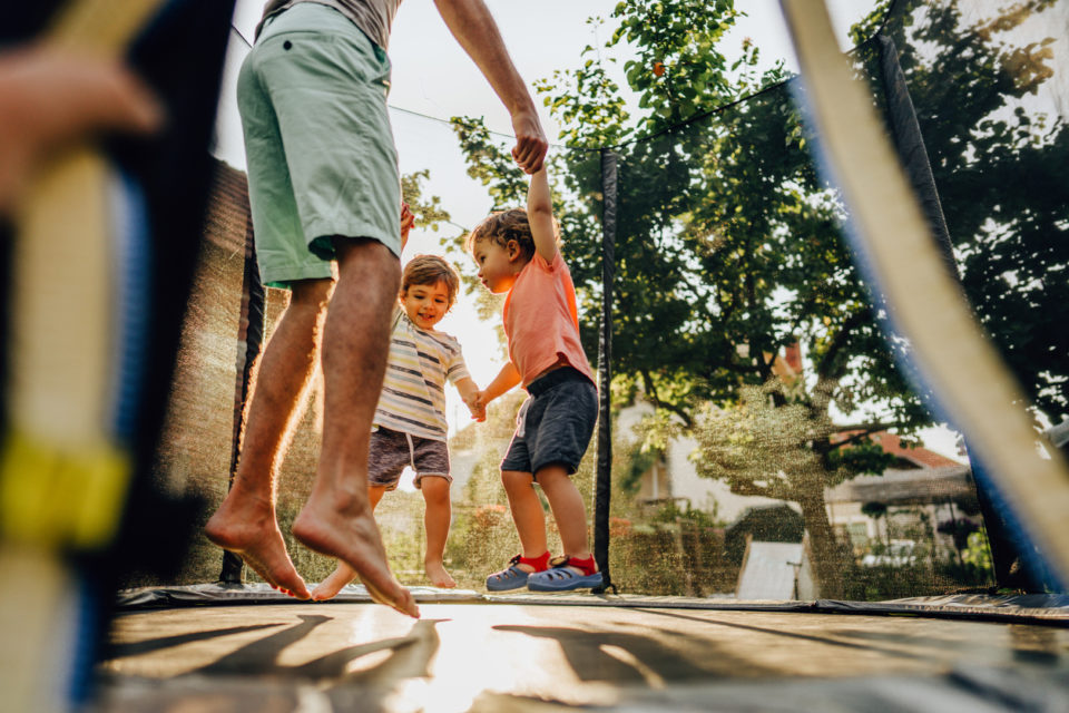 Photo of father and his boys having fun on the trampoline