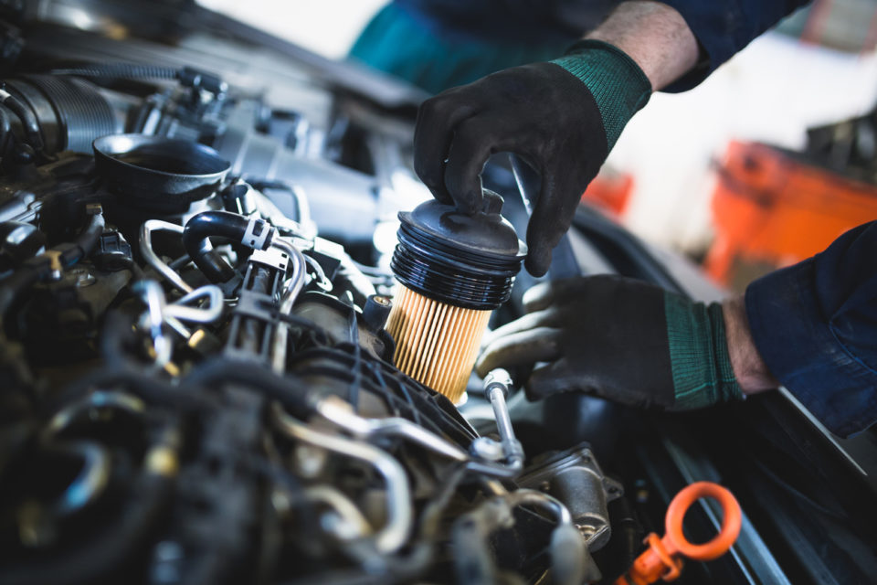 Close up hands of unrecognizable mechanic doing car service and maintenance.