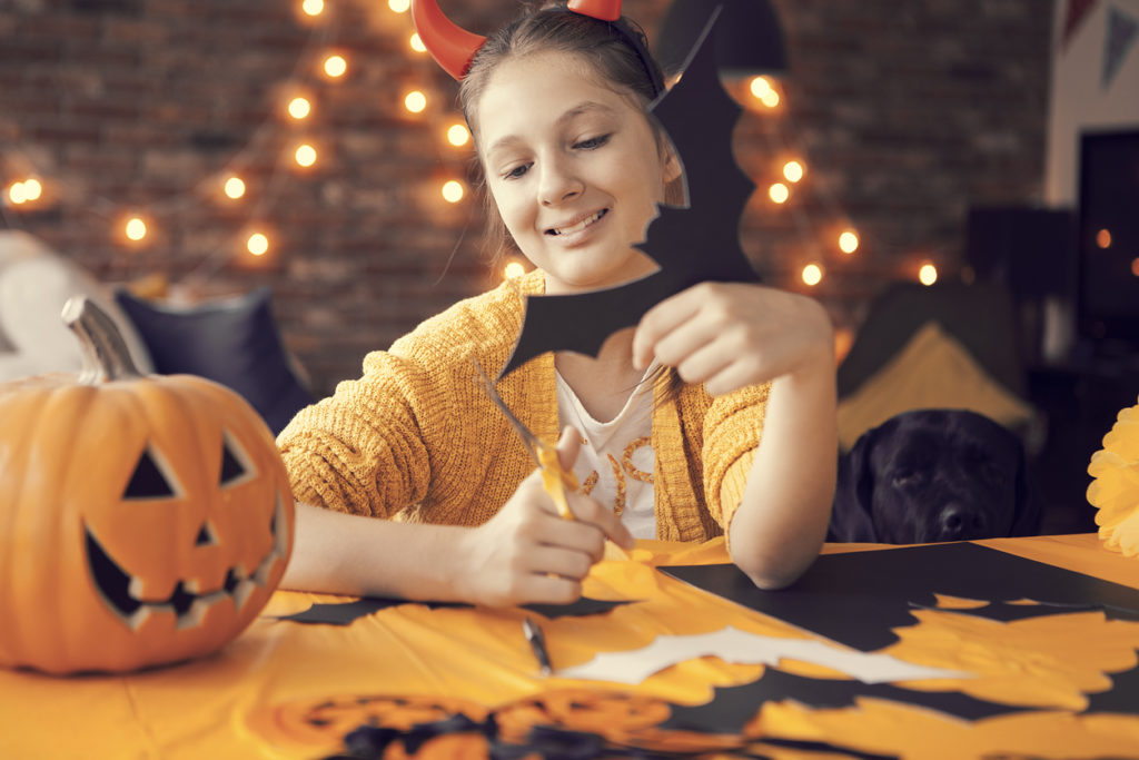 person cutting paper bats with jack-o-lantern