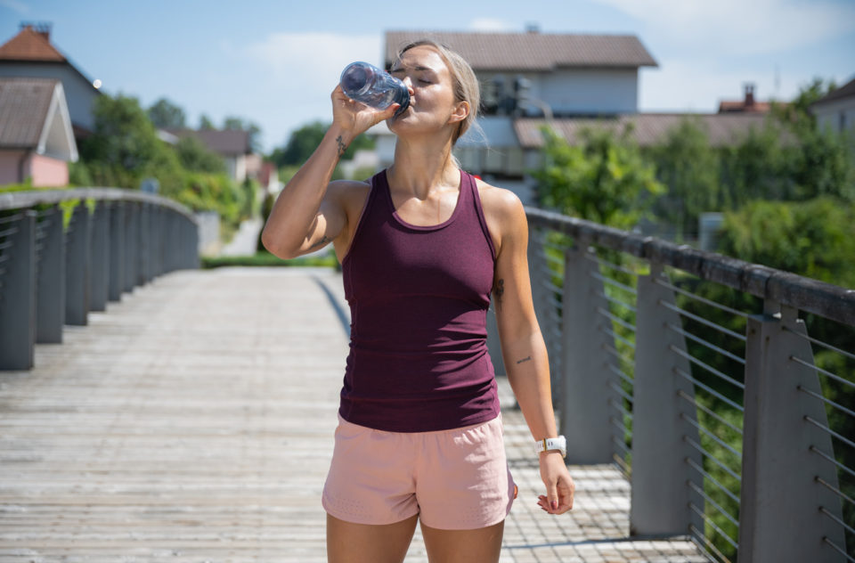 Tired sporty woman drinking water