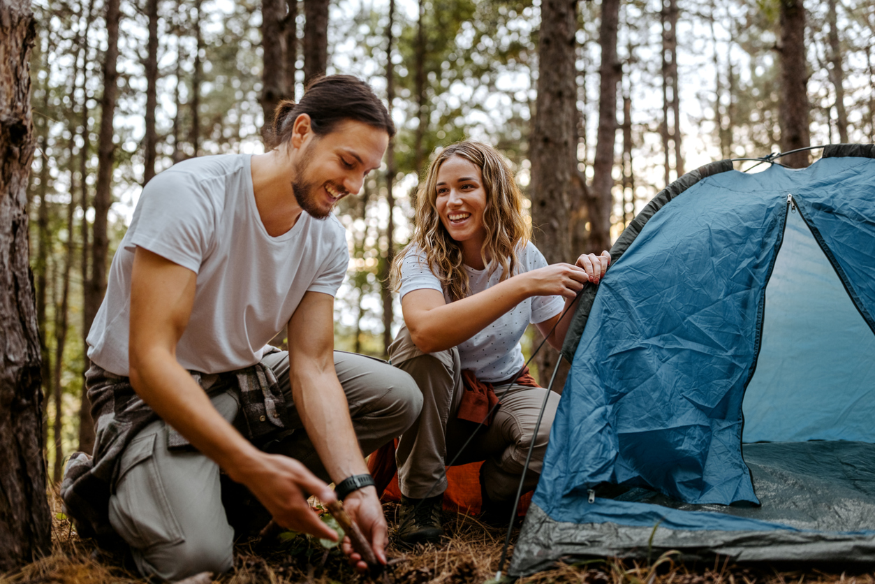 Couple building tent in forest during hike