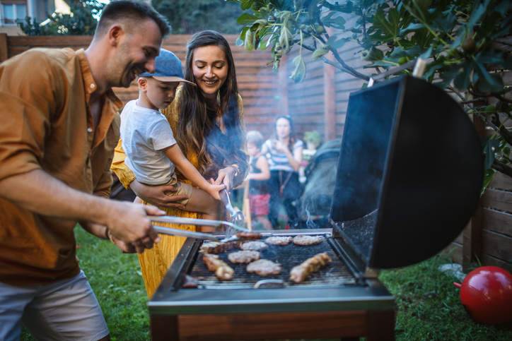 How to Host the Best BBQ.  Photo of young happy family having a barbecue party in backyard