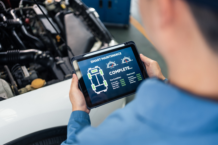 Close up of Automotive mechanic running diagnostics software on tablet. Asian young vehicle service manager worker work in mechanics garage, check and maintenance to repair the engine car in workshop.